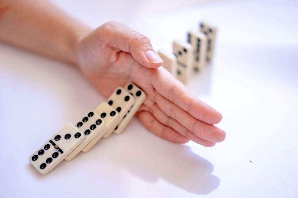 Hand stops dominoes from all falling over